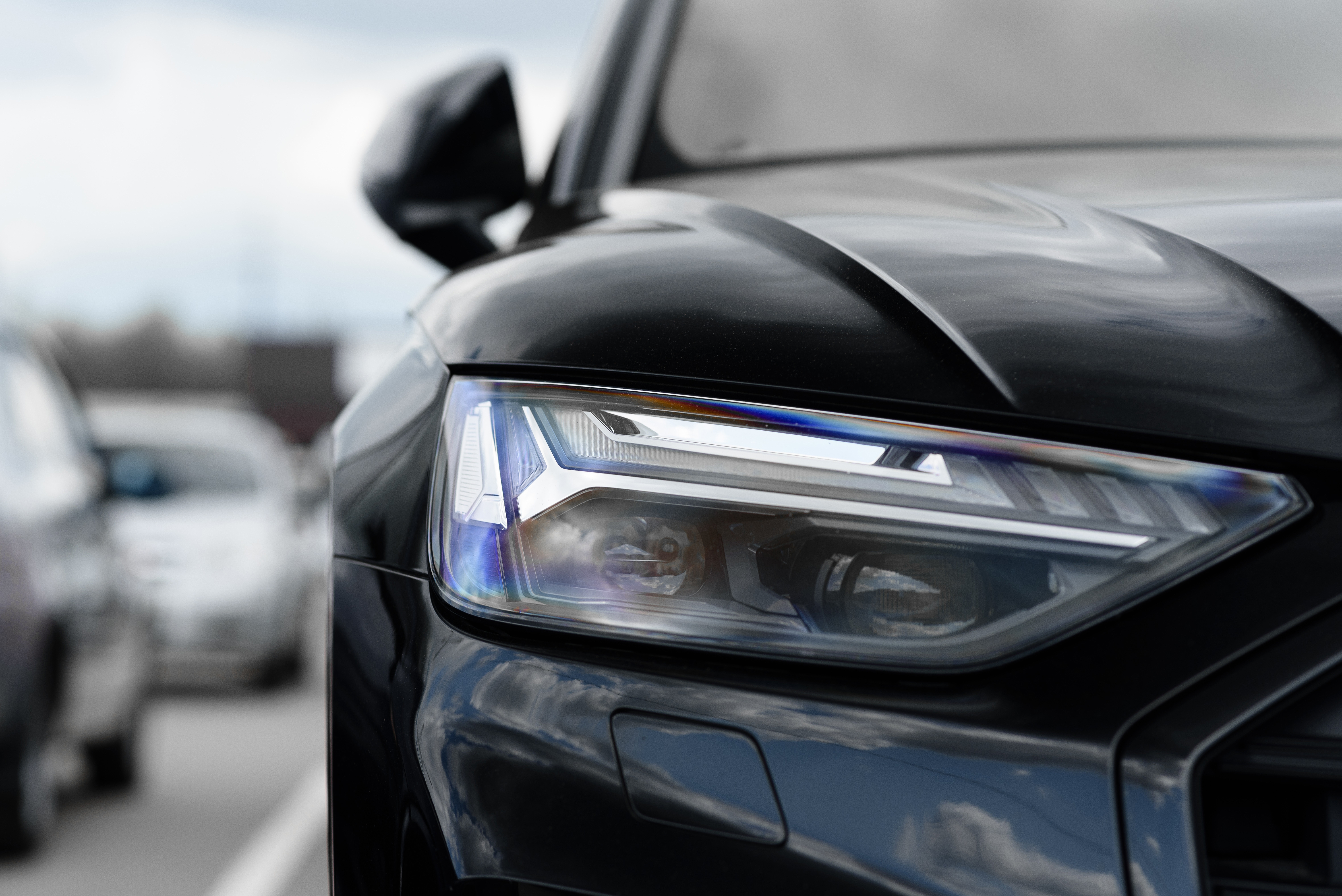 Detalhes de um farol de um carro preto alertando sobre direção segura