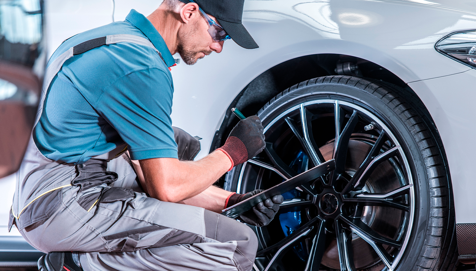 Imagem de um mecânico realizando manutenção automotiva em uma roda de um carro